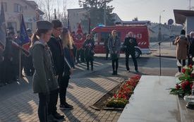 złożenie kwiat&oacute;w pod pomnikiem w centrum tłuchowa