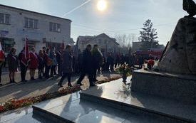 złożenie kwiat&oacute;w pod pomnikiem w centrum tłuchowa